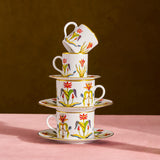 Stack of ceramic cups with floral designs on a pink surface and brown background