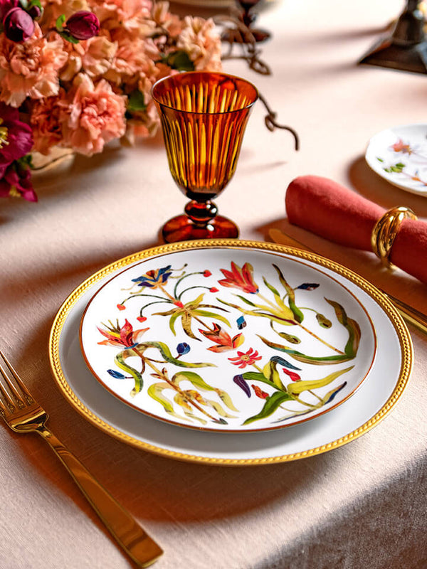 Decorative floral plate on a table with flowers and cutlery