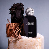 black bell shaped glass bottle with round crackle top styled with a moody blue background 